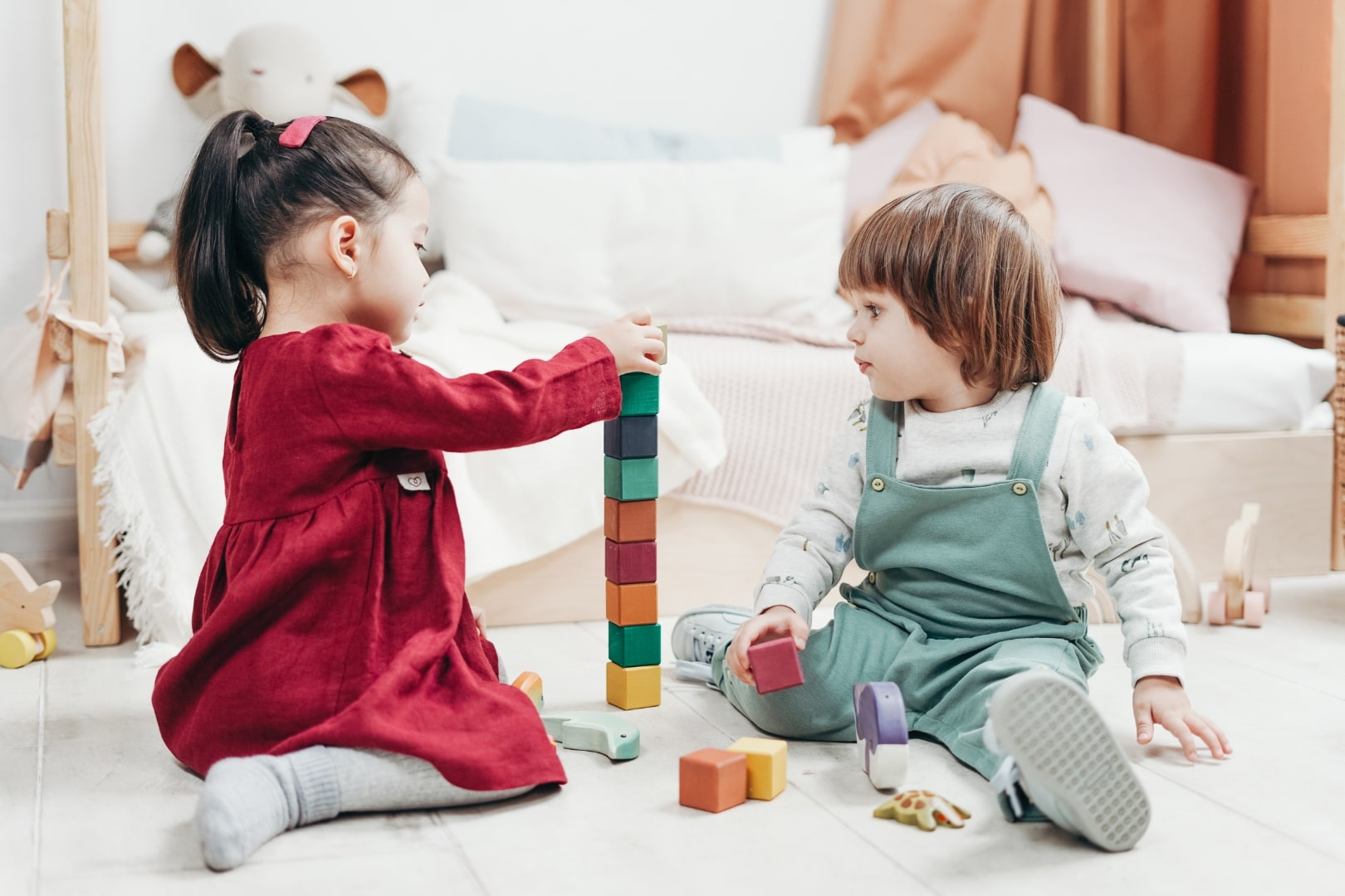 Two children playing with wooden blocks in a room.